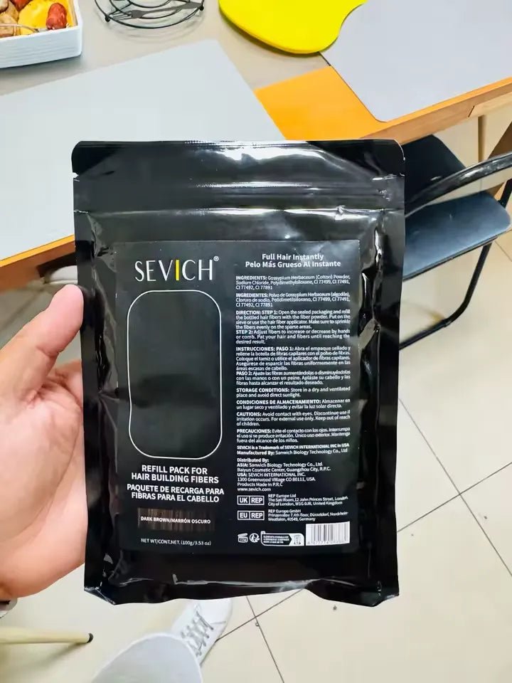 Uma embalagem preta do produto é exibida na mão, com o verso voltado para a câmera.