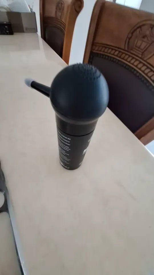 Um aplicador preto é mostrado em pé sobre uma mesa clara.